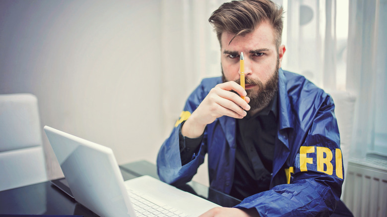 펜을 자세히 조사하는 FBI 요원