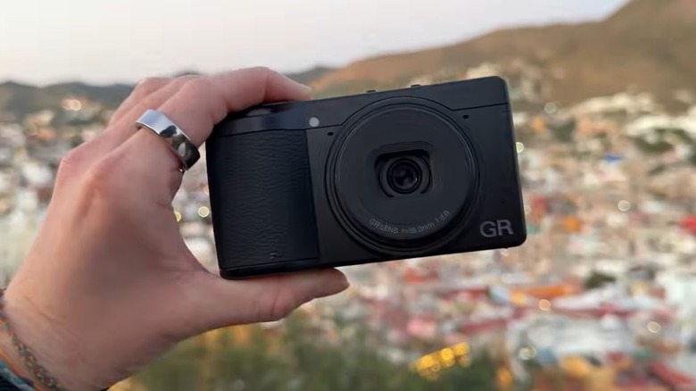 밖에서 Ricoh GR IV 카메라를 들고 있는 사람.