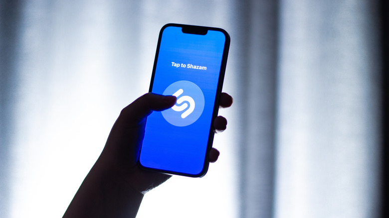 Shazam 앱을 실행하는 휴대폰을 들고 있는 사람