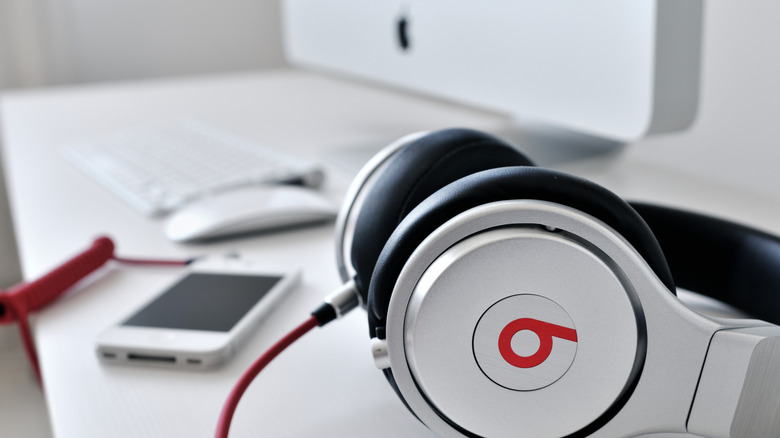 iPhone과 iMac 옆 테이블에 놓여 있는 Beats Audio 헤드폰