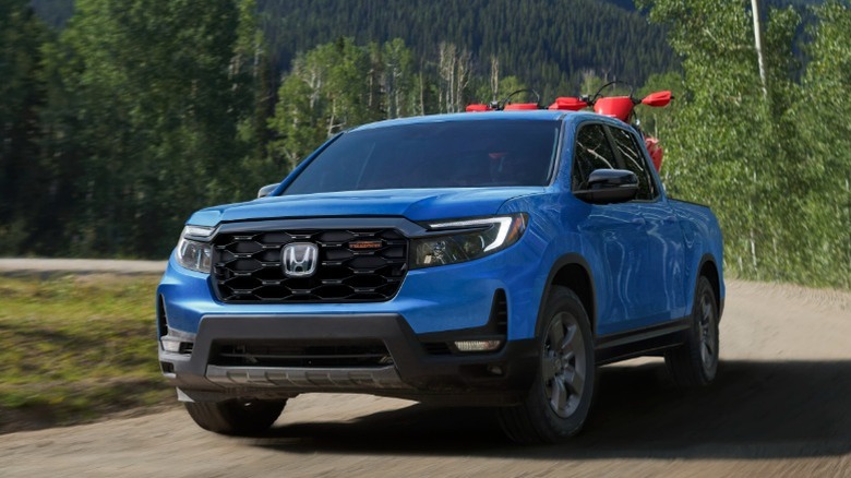 숲이 우거진 비포장 도로를 질주하는 Blue Honda Ridgeline