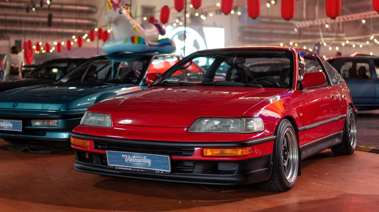 실내 자동차 쇼에 주차된 빨간색 Honda CRX의 전면 3/4 모습.