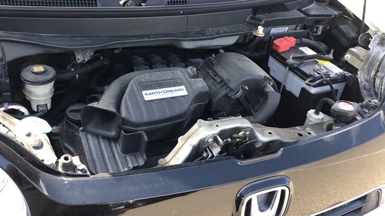 Earth Dreams Technology 커버 배지를 부착한 Honda S07A 엔진 베이는 후드가 열려 있는 소형 일본 경차처럼 보이는 자동차 내부에 앉아 있습니다.