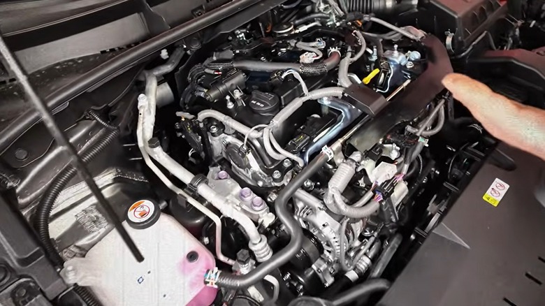 호스, 배선 및 배관으로 둘러싸인 노출된 3기통 장치가 밀집되어 있는 Toyota G16E-GTS 엔진 베이입니다.
