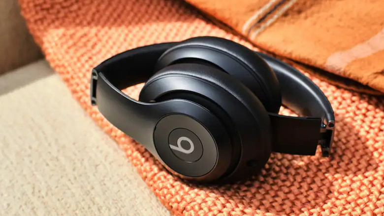 갈색 소파 위의 주황색 담요 위에 놓인 Beats 헤드폰 한 쌍