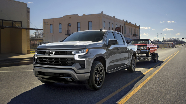 거리에 있는 은색 Chevy Silverado 1500 견인 트레일러의 전면 3/4 모습.