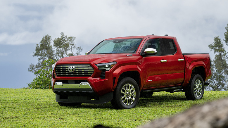 언덕 꼭대기에 주차된 빨간색 Toyota Tacoma 하이브리드의 전면 3/4 뷰.