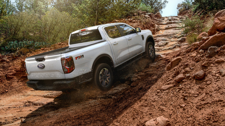 오프로드 트레일을 오르는 흰색 Ford Ranger FX4의 후면 모습.