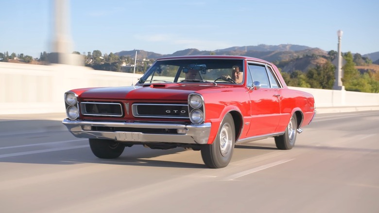 고속도로에서 빨간색 Pontiac GTO Royal Bobcat을 운전하는 Jay Leno
