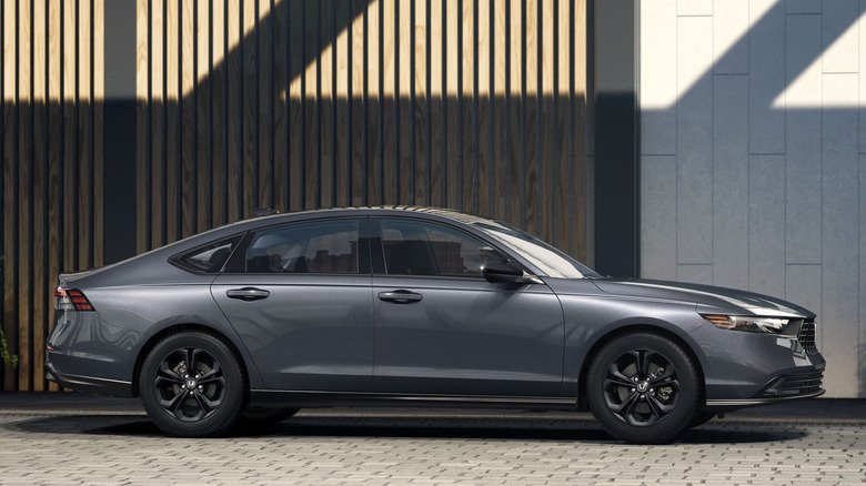 건물 앞에 주차된 회색 2025 Honda Accord SE의 측면 모습.