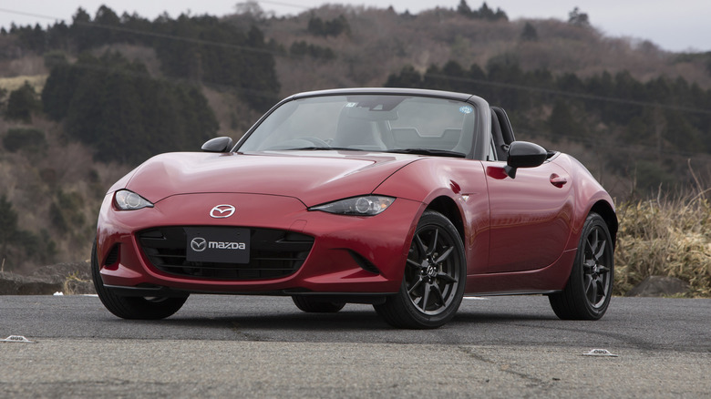 언덕 앞에 주차된 빨간색 Mazda MX-5 로드스터.