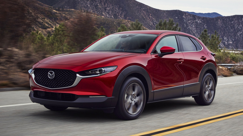 빨간색 Mazda CX-30 SUV가 시골 도로를 주행하고 있습니다.