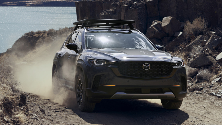 회색 Mazda CX-50 SUV가 오프로드를 주행하고 있습니다.