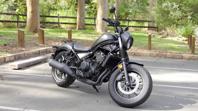 주차장에 있는 검은색 Honda Rebel 500, 킥스탠드가 세워진 전면 3/4 뷰