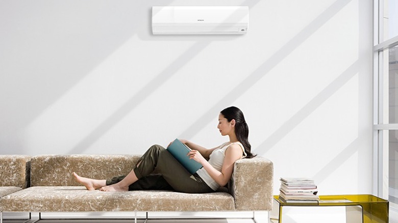 벽에 걸린 Hitachi AC, 바로 아래 소파에서 휴식을 취하고 있는 사람