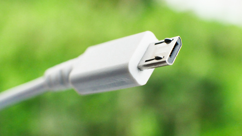 배경에 잔디가 있는 흰색 마이크로 USB 케이블