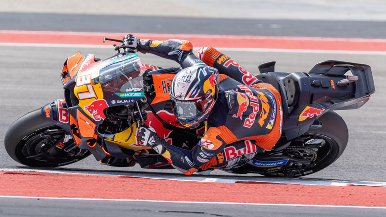모퉁이에 세게 기대어 있는 Moto GP Red Bull 자전거 라이더
