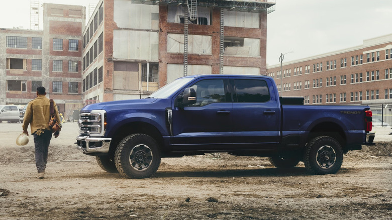 한 남자가 파란색 Ford Super Heavy Duty 옆을 지나가고 있습니다.