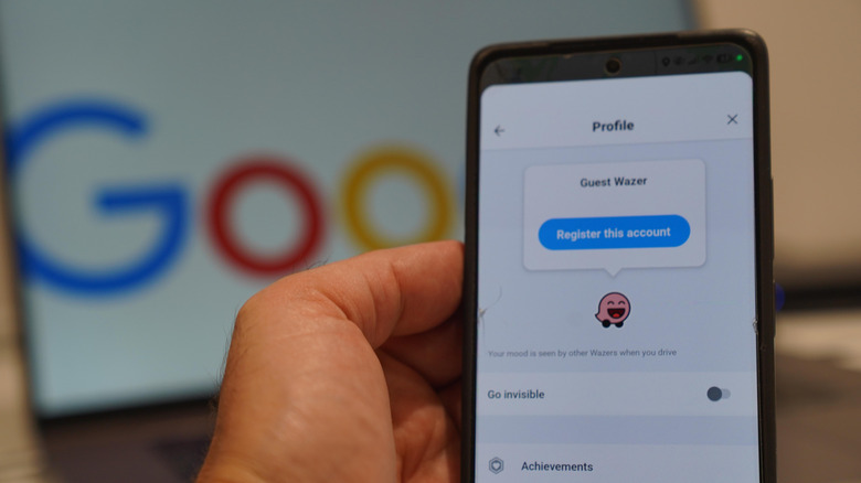 노트북 앞에 Waze 프로필 화면이 표시된 스마트폰을 들고 있는 사람