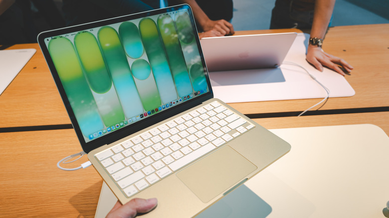 Apple의 MacBook Neo 노트북을 들고 있는 사람