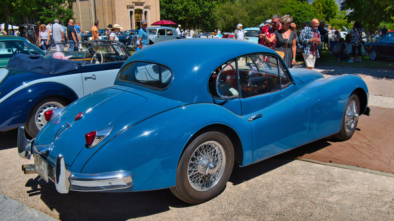 야외 오토쇼 설정에서 Jaguar XK140 쿠페의 후면 3/4 뷰