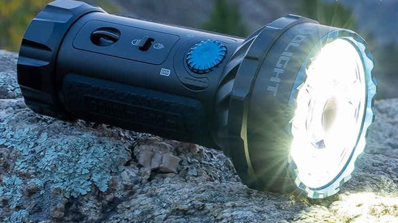 바위 위에 올려진 Olight Marauder Mini 손전등.