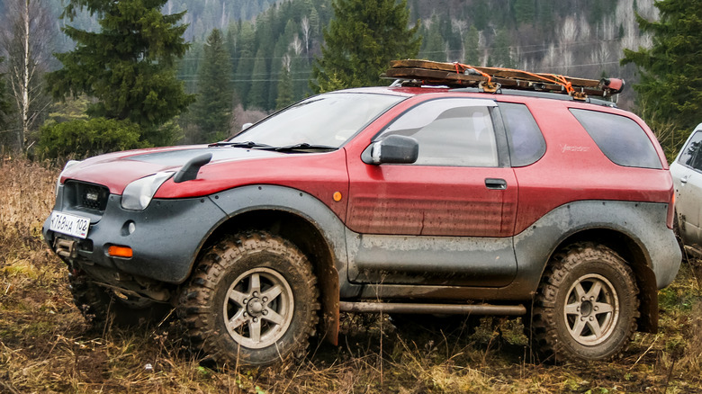 들판에 주차된 진흙투성이의 빨간색 Isuzu VehiCross