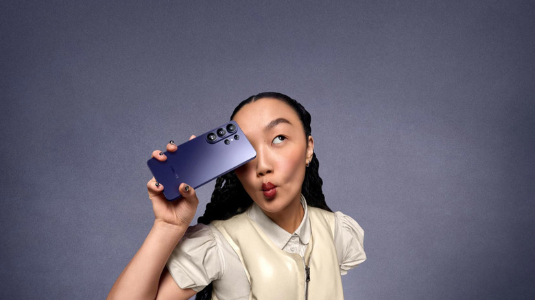 회색 스튜디오 배경에서 Samsung S26 Ultra를 들고 있는 소녀