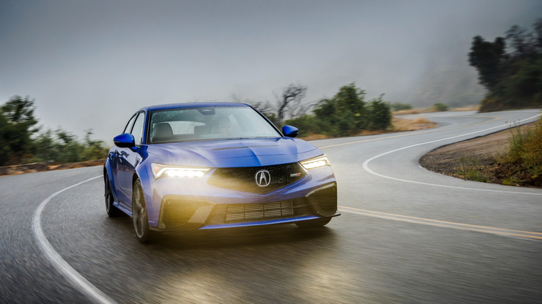 파란색의 Acura Integra Type S가 비오는 도로를 주행하고 있습니다.