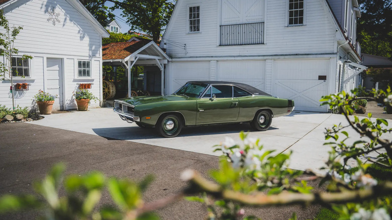 짙은 금속성 녹색 1969 Dodge Charger R/T가 오래된 백악관 앞 진입로에 주차되어 있습니다.