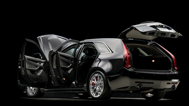 문과 후드가 열린 상태로 스튜디오에 주차된 검은색 Cadillac CTS-V 왜건의 후면 3/4 뷰.