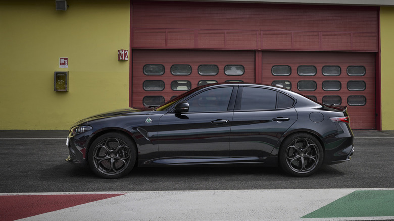 경주 트랙에 주차된 검은색 Alfa Romeo Giulia Quadrifoglio의 측면 모습.