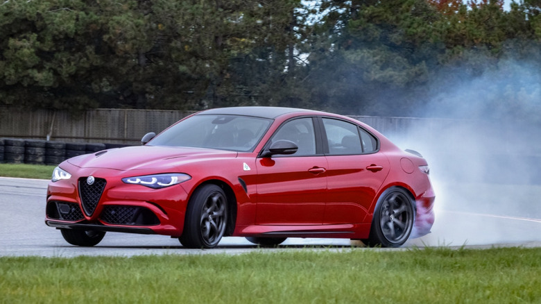 경주 트랙에서 표류하는 빨간색 Alfa Romeo Giulia Quadrifoglio의 전면 3/4 뷰.