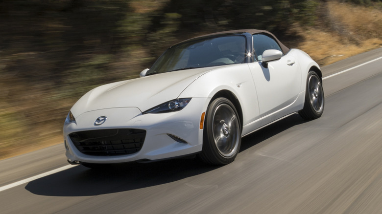 고속도로를 주행하는 흰색 Mazda MX-5 Miata의 전면 3/4 뷰.