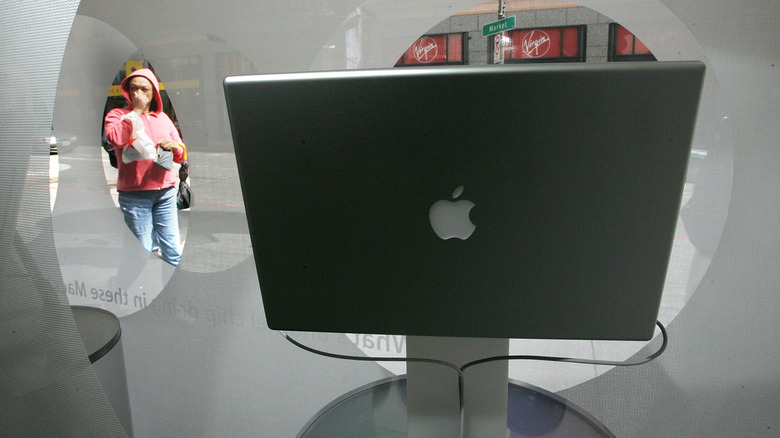 금속성 사과 로고가 표시된 구형 Apple MacBook을 창문 너머로 바라보는 여성