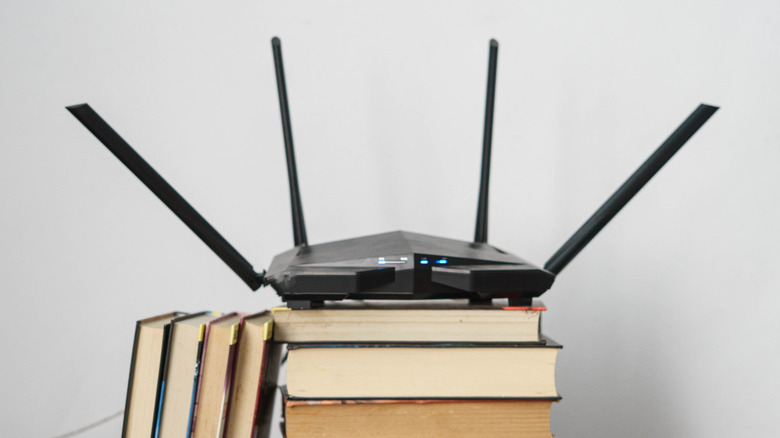 책 더미 위에 앉아 있는 Wi-Fi 라우터