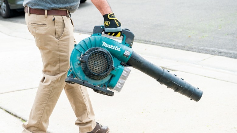 진입로에서 마키타 송풍기를 사용하는 사람.