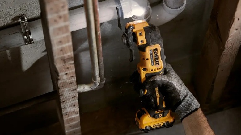 DeWalt Multi-tool을 사용하여 PVC를 절단하는 사람