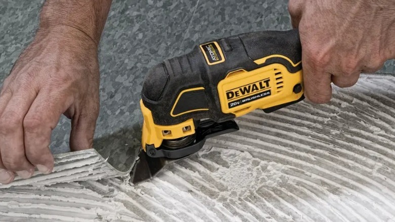 그라우팅된 바닥을 제거하기 위해 DeWalt Multi-tool을 사용하는 사람