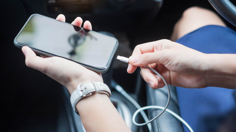 충전 및 Android Auto용 USB 케이블을 사용하여 휴대전화를 자동차에 연결하는 사람