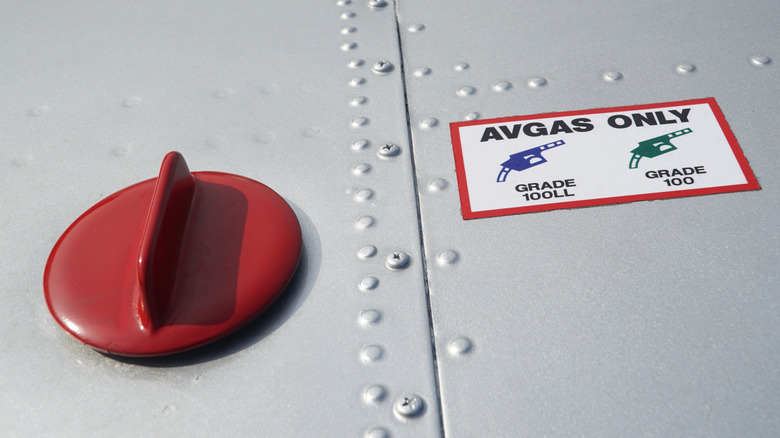 항공기의 연료 탱크 필러 캡을 닫고 그 옆에 avgas only라는 스티커가 붙어 있습니다.