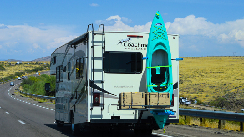 보관 상자와 뒤쪽에 카약이 묶인 Coachmen RV의 후면 모습