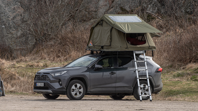 루프탑 텐트가 있는 회색 Toyota RAV4의 측면 모습.