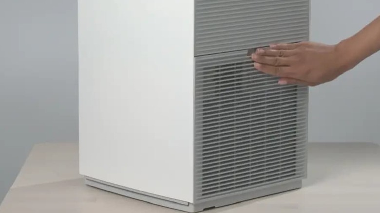 Daikin 공기청정기의 통풍구를 만지는 사람.
