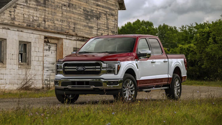 낡은 건물 앞 시골 비포장 도로에 주차된 투톤 페인트의 2027 Ford F-150