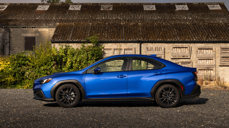 오래된 헛간 앞에 주차된 파란색 2026 Subaru WRX의 측면 모습