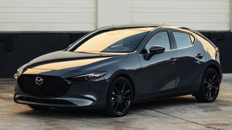 어두운 곳에서 콘크리트 위에 주차된 검은색 2026 Mazda3