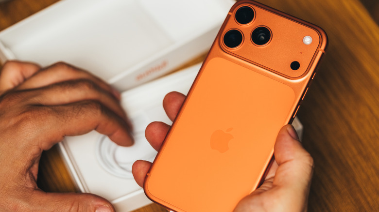 박스를 풀고 있는 주황색 iPhone 17.