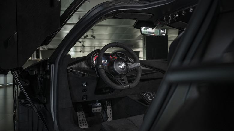 도어가 열려 있는 Alfa Romeo 33 Stradale Perla Nero의 운전석 클로즈업 샷
