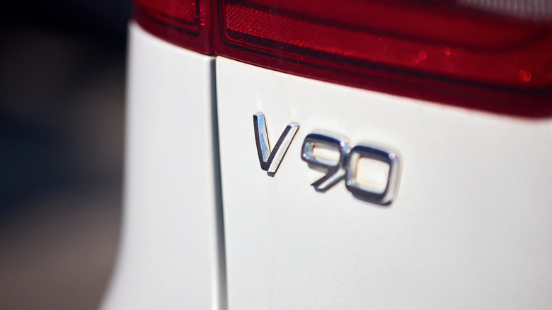 흰색 모델 후면의 볼보 V90 엠블럼 클로즈업